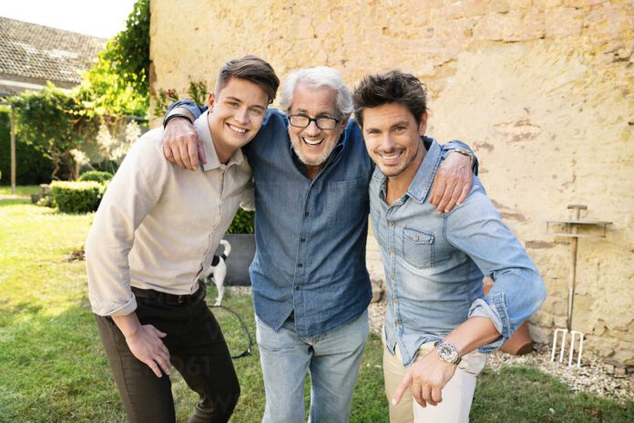 Portrait of three happy men of different age embracing in garden